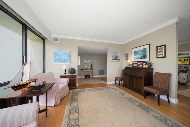 sitting room with crown molding, visible vents, and light wood-style floors