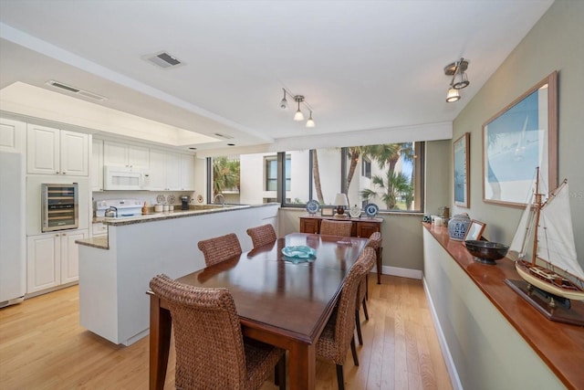 dining area with light wood-type flooring, visible vents, baseboards, and wine cooler