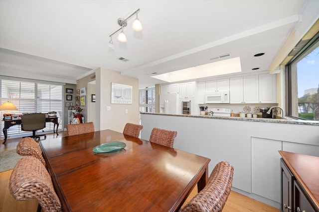 dining space with light wood finished floors, visible vents, and crown molding