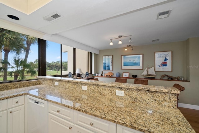 kitchen with light stone countertops, white cabinetry, visible vents, and dishwasher