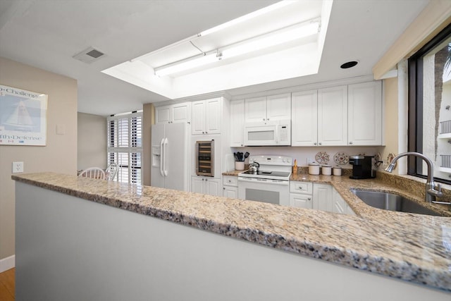 kitchen with visible vents, white cabinets, a sink, light stone countertops, and white appliances