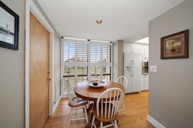 dining room with light wood-style flooring, baseboards, a wall of windows, and recessed lighting