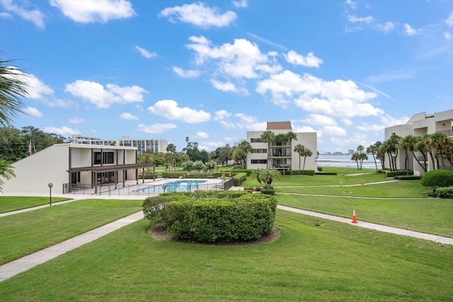 view of home's community with a water view, a patio area, a swimming pool, and a yard