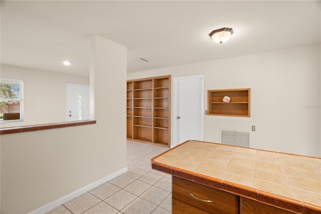 kitchen featuring built in shelves, light tile patterned flooring, and tile countertops