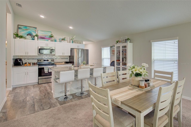 dining area with vaulted ceiling, recessed lighting, visible vents, and light wood-style floors