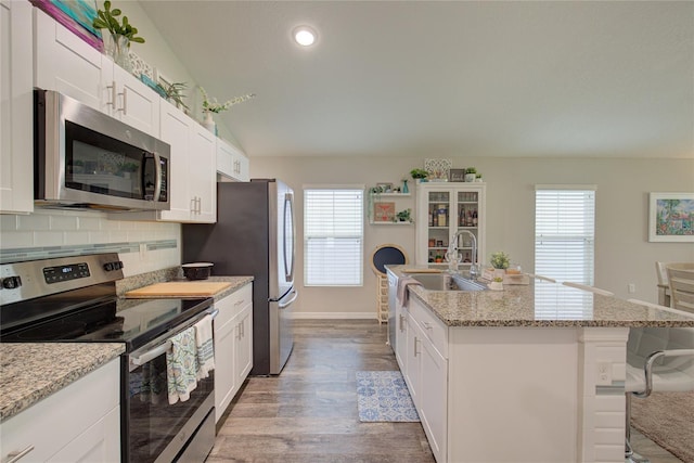 kitchen with stainless steel appliances, a sink, a kitchen island with sink, and white cabinets