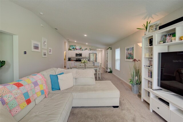 living area with light carpet, vaulted ceiling, and a textured ceiling