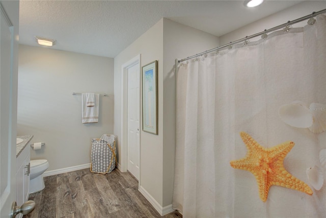 full bathroom featuring baseboards, toilet, wood finished floors, a textured ceiling, and vanity