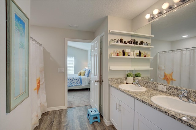 full bath featuring a textured ceiling, wood finished floors, ensuite bath, and a sink