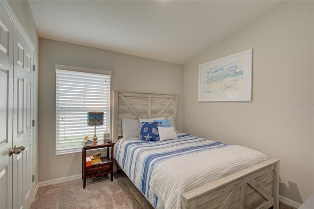 carpeted bedroom with lofted ceiling and baseboards