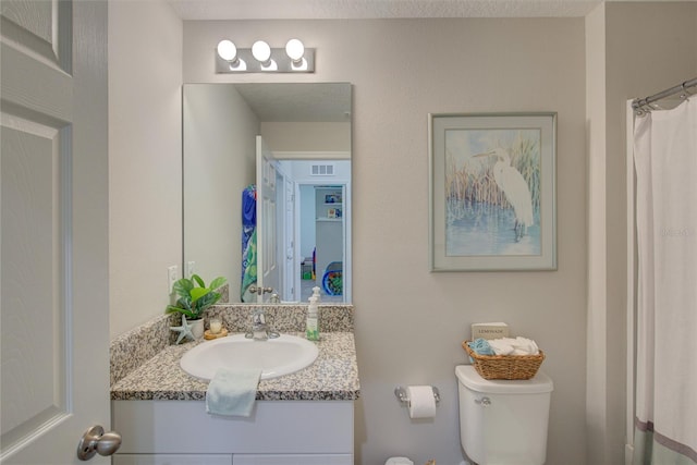 bathroom with visible vents, vanity, and toilet