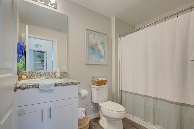 full bath with a textured ceiling, toilet, wood finished floors, vanity, and visible vents