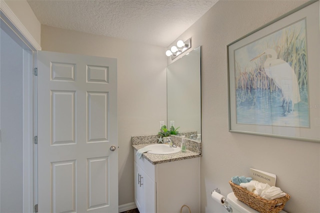 half bath with vanity, toilet, and a textured ceiling