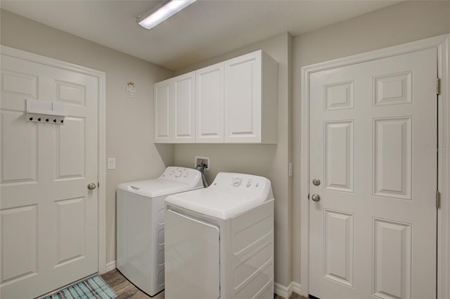 washroom featuring washing machine and dryer, cabinet space, and baseboards