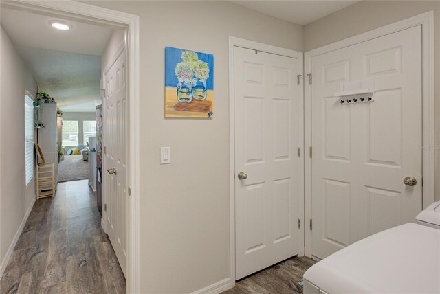 bedroom featuring dark wood-style flooring, washer and dryer, and baseboards