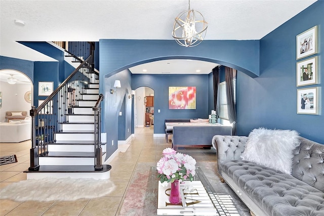 living room featuring a textured ceiling, ceiling fan with notable chandelier, and tile patterned flooring