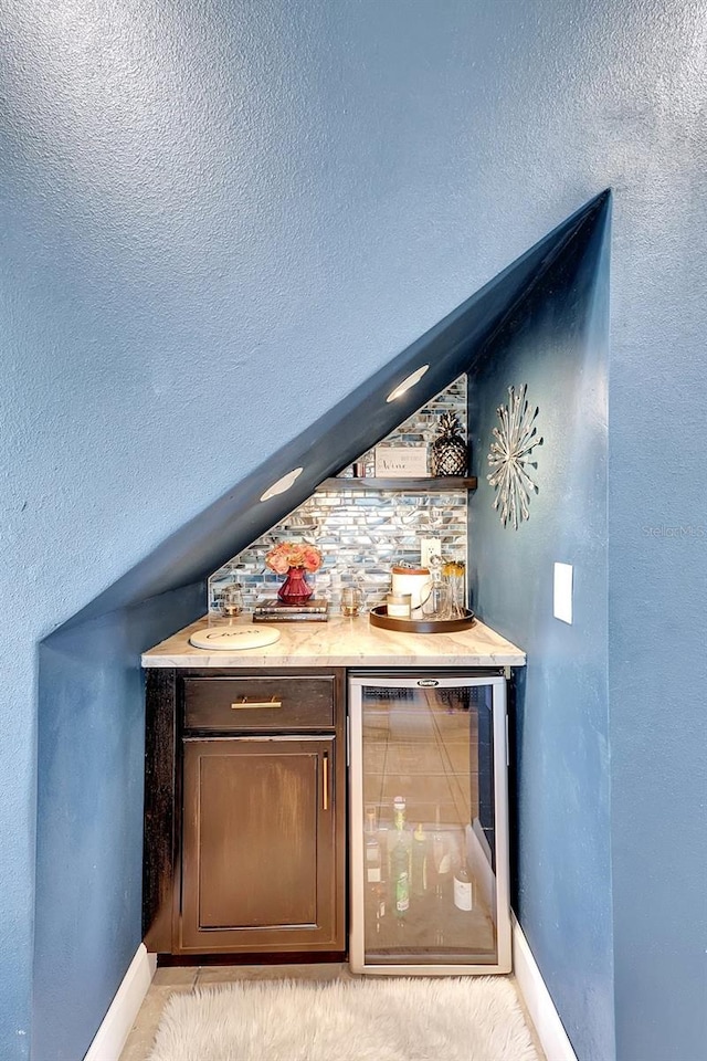 bar with dark brown cabinets, beverage cooler, and light tile patterned floors