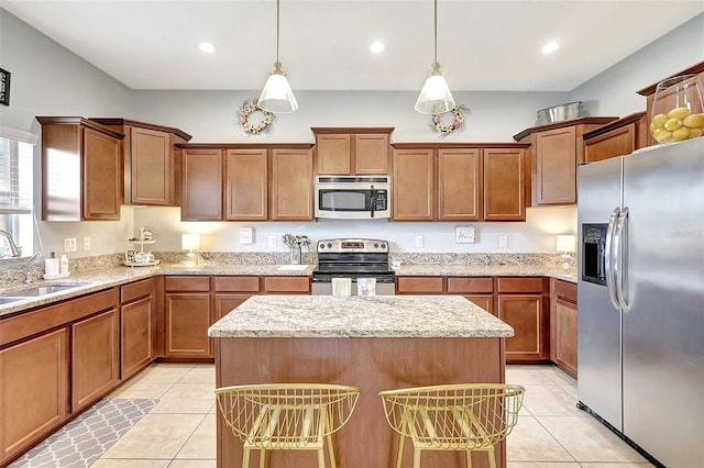 kitchen featuring appliances with stainless steel finishes, sink, pendant lighting, light tile patterned floors, and a kitchen island