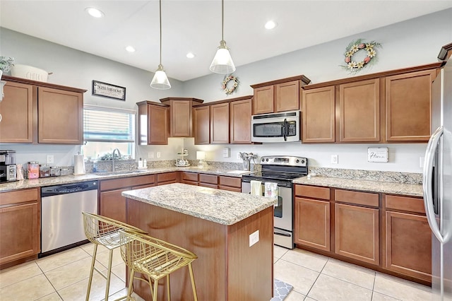 kitchen featuring stainless steel appliances, sink, a kitchen island, light tile patterned floors, and a kitchen breakfast bar