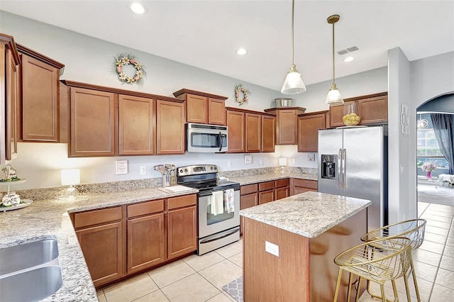 kitchen with stainless steel appliances, pendant lighting, light tile patterned floors, light stone countertops, and a center island