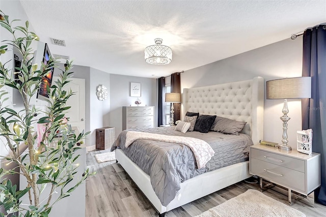 bedroom with light hardwood / wood-style floors and a textured ceiling