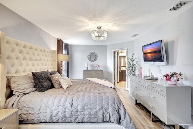 bedroom featuring connected bathroom and light hardwood / wood-style floors