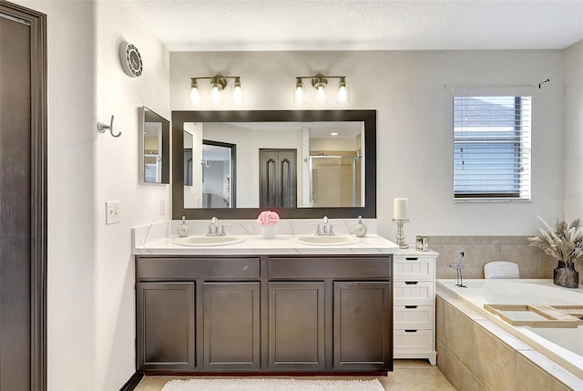 bathroom featuring a textured ceiling, tile patterned flooring, tiled bath, and double sink vanity