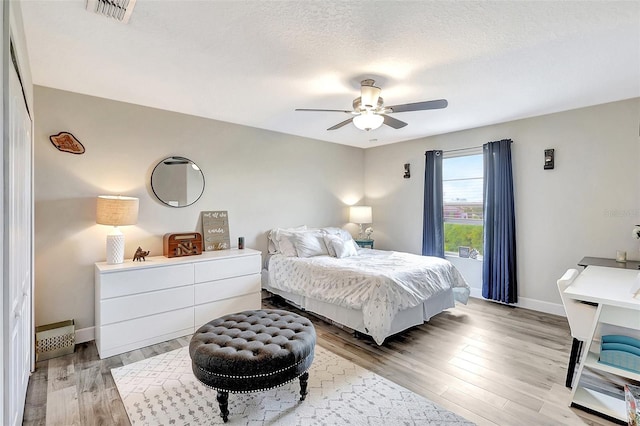 bedroom featuring light wood-type flooring, ceiling fan, and a textured ceiling