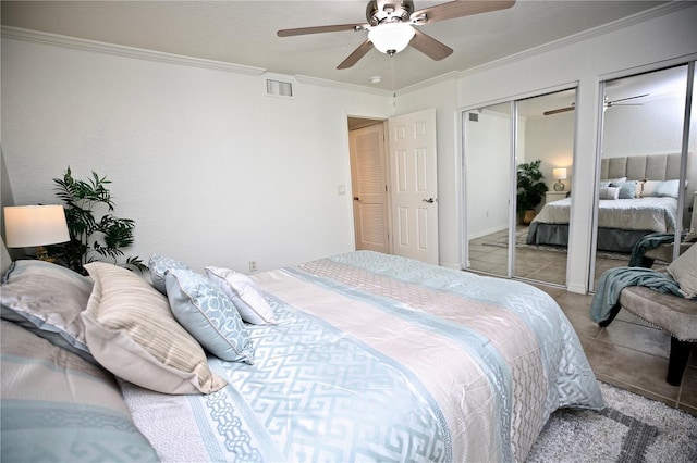 bedroom featuring ceiling fan, ornamental molding, light tile patterned floors, and two closets