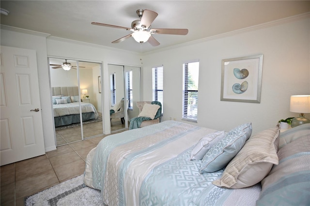 tiled bedroom featuring two closets, ceiling fan, and ornamental molding