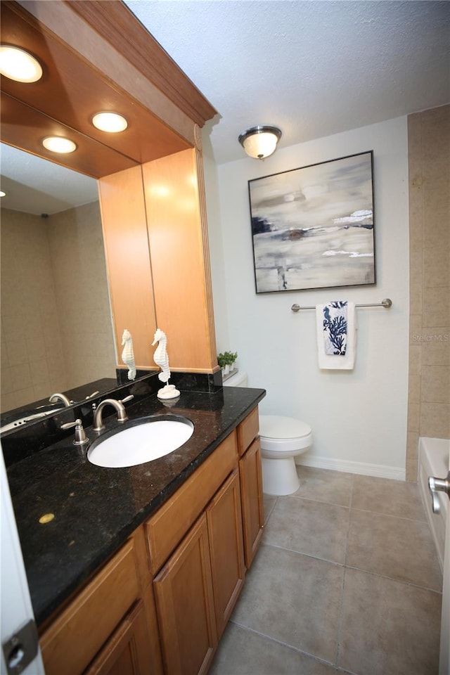 bathroom featuring tile patterned floors, a bathtub, vanity, and toilet