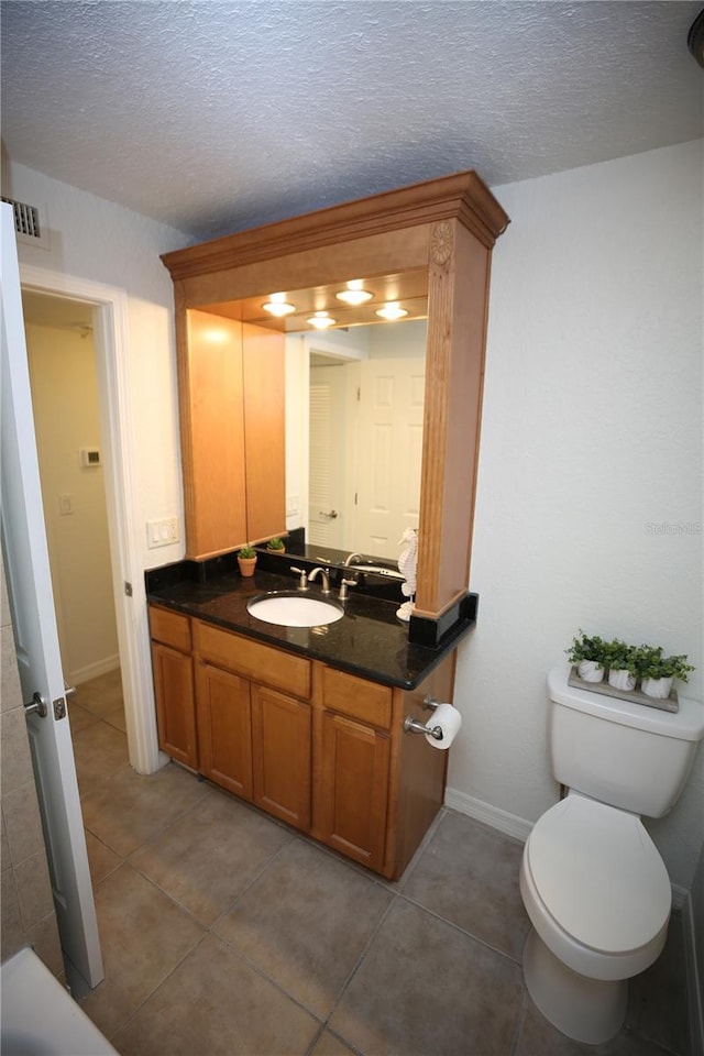 bathroom featuring tile patterned flooring, vanity, toilet, and a textured ceiling