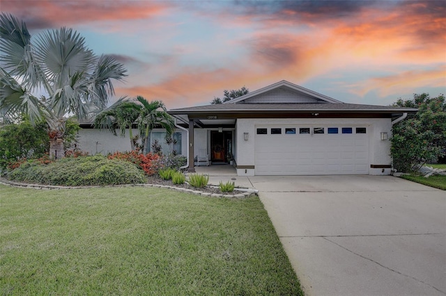 ranch-style house with a garage and a yard