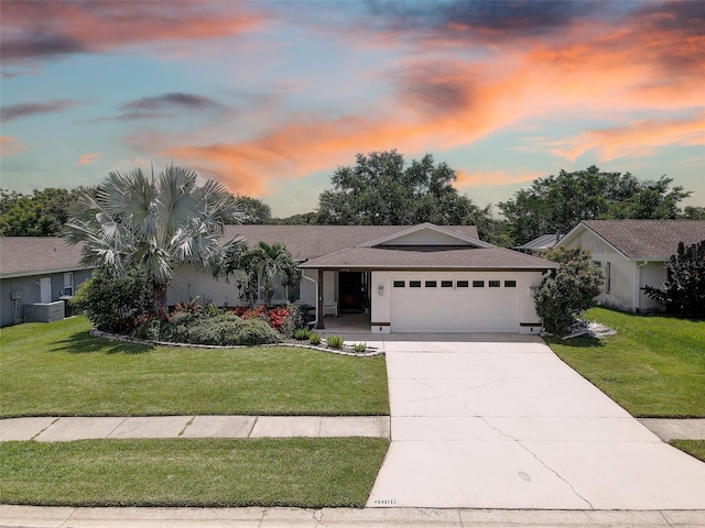 single story home with a garage, central air condition unit, and a lawn