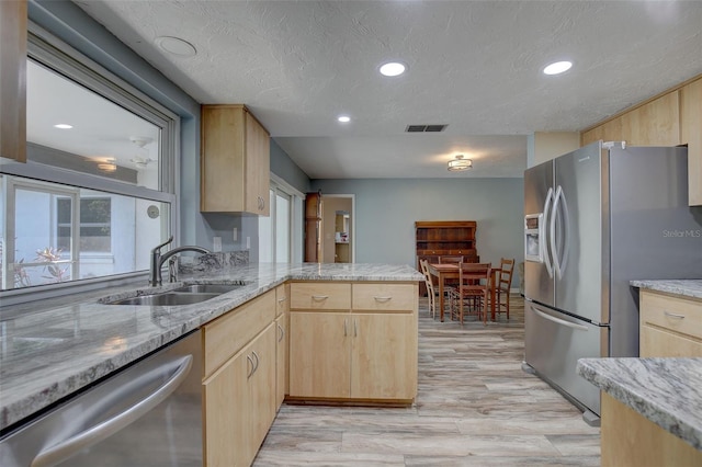 kitchen featuring sink, stainless steel appliances, light stone countertops, kitchen peninsula, and light brown cabinets