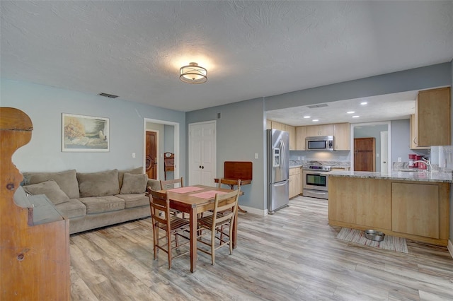 dining room with a textured ceiling and light hardwood / wood-style flooring