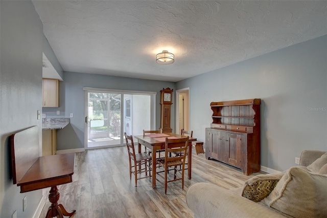 dining room featuring a textured ceiling and light wood-type flooring