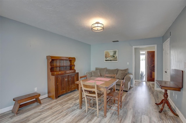 dining room with a textured ceiling and light hardwood / wood-style floors