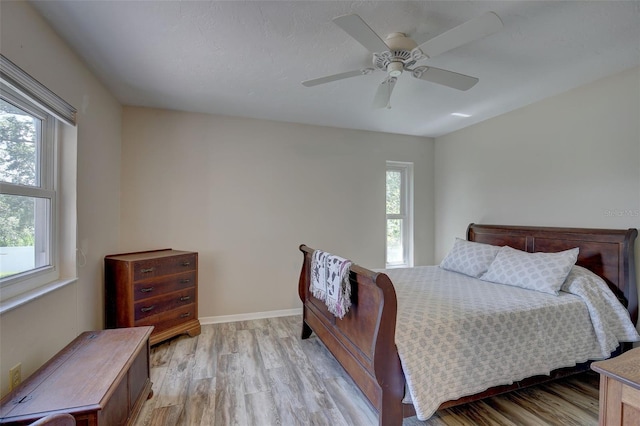 bedroom featuring ceiling fan, multiple windows, and light wood-type flooring