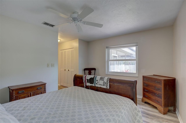 bedroom featuring light hardwood / wood-style floors, a textured ceiling, ceiling fan, and a closet