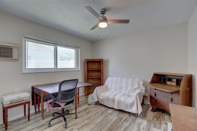 office area featuring a textured ceiling, light hardwood / wood-style flooring, an AC wall unit, and ceiling fan