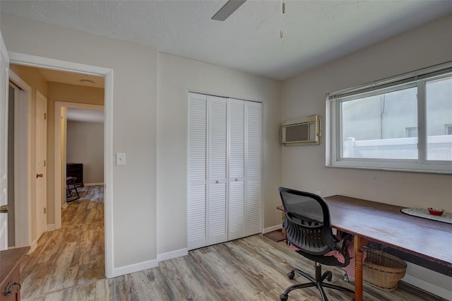 office area with ceiling fan, light wood-type flooring, and an AC wall unit