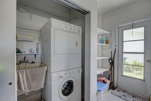 laundry area featuring plenty of natural light, stacked washing maching and dryer, and sink