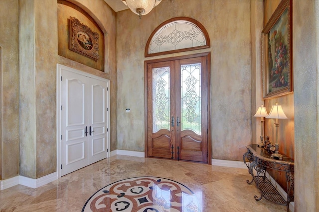 tiled entryway with a high ceiling, french doors, and plenty of natural light