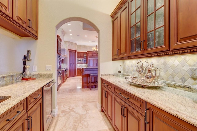 kitchen featuring beverage cooler, light stone countertops, ornamental molding, and light tile patterned floors