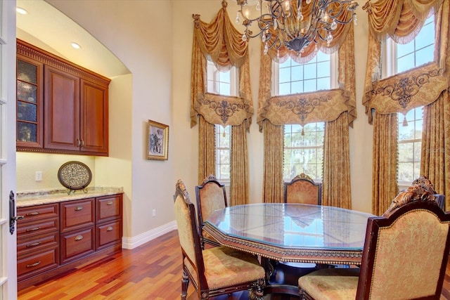 dining room featuring a towering ceiling, a notable chandelier, and light hardwood / wood-style flooring