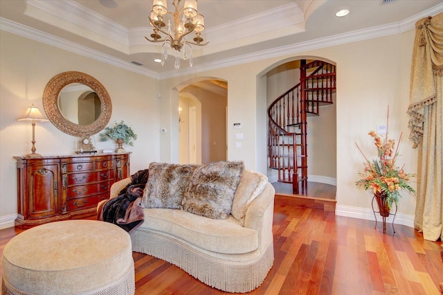 living room featuring hardwood / wood-style flooring, a notable chandelier, crown molding, and a tray ceiling