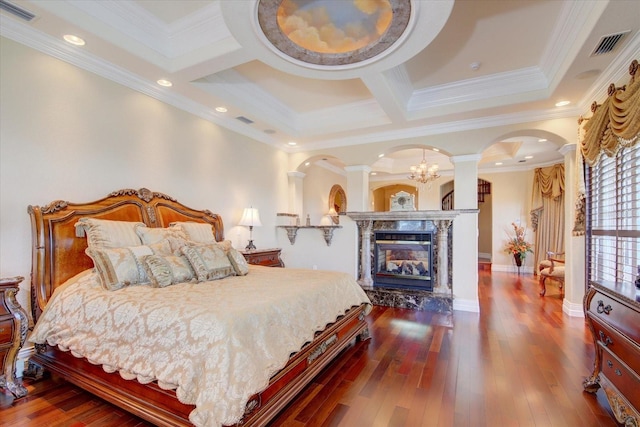 bedroom featuring crown molding, hardwood / wood-style floors, decorative columns, coffered ceiling, and a high end fireplace