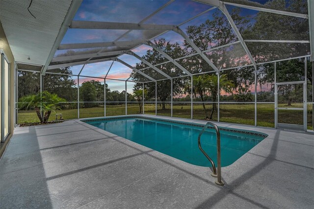 pool at dusk featuring a patio, a yard, and glass enclosure