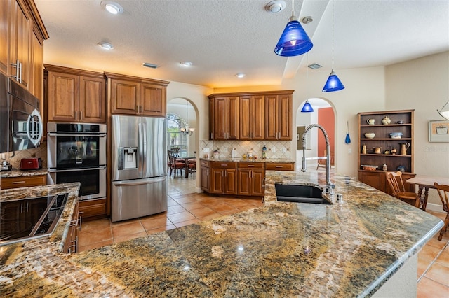 kitchen with arched walkways, stainless steel appliances, a sink, visible vents, and backsplash